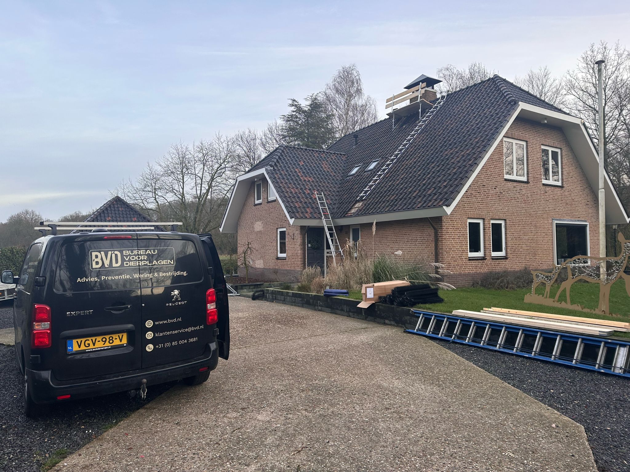Bedrijfsbusje van 'Bureau voor Dierplagen' geparkeerd voor een huis met een ladder tegen het dak, mogelijk voor werkzaamheden om het dak te beschermen tegen steenmarters en vogels.