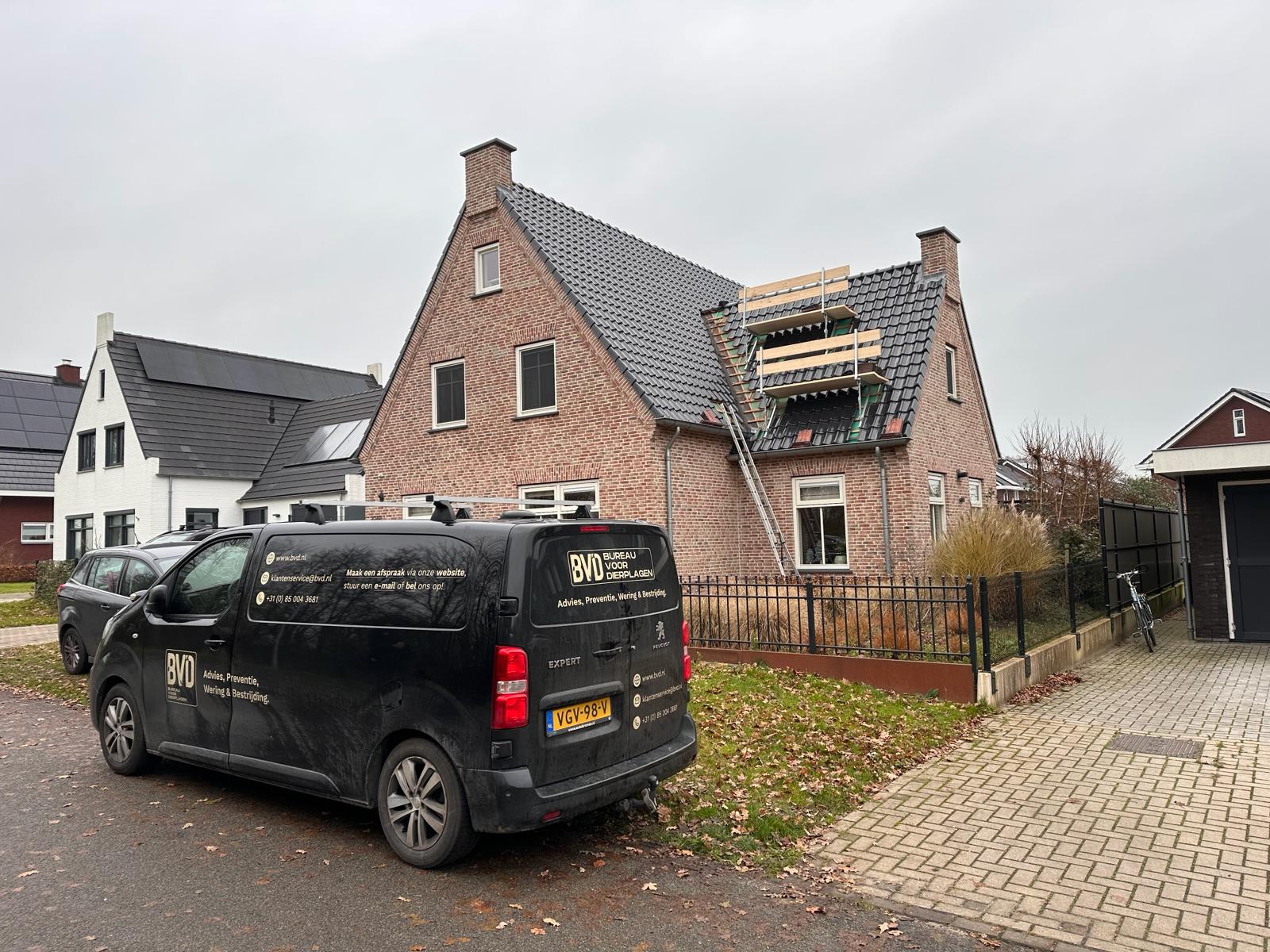 Een bedrijfsbusje geparkeerd voor een huis met een ladder tegen de gevel, mogelijk voor onderhoudswerkzaamheden.
