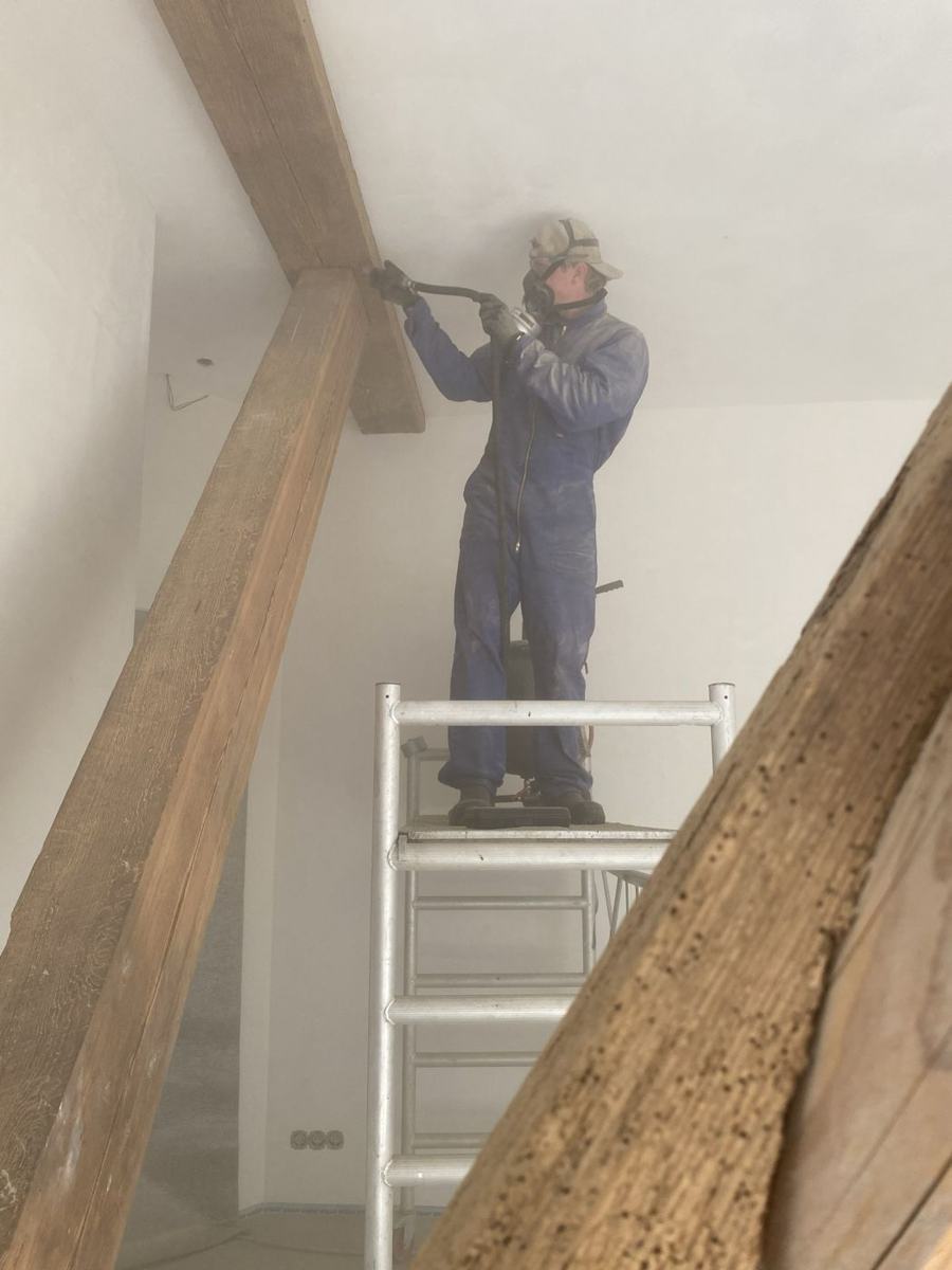 Medewerker behandelt een balk vanaf een rolsteiger