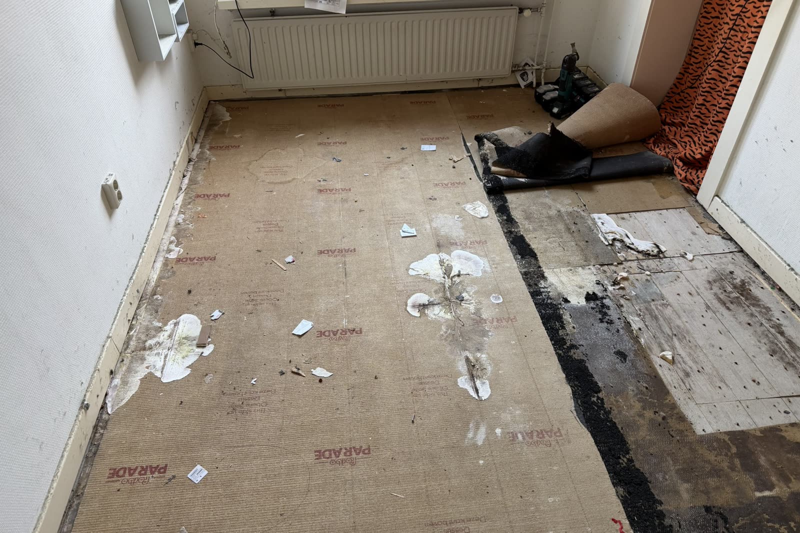 Kamer met deels opengelegde vloer en aangetaste ondervloer langs de wand